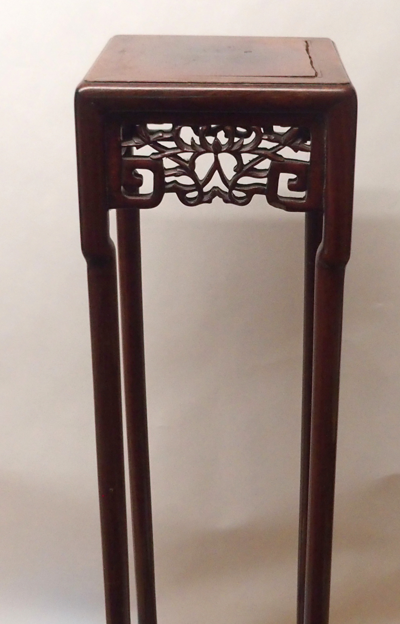 A CHINESE HARDWOOD VASE STAND the square top above foliate and key pattern frieze and on slender