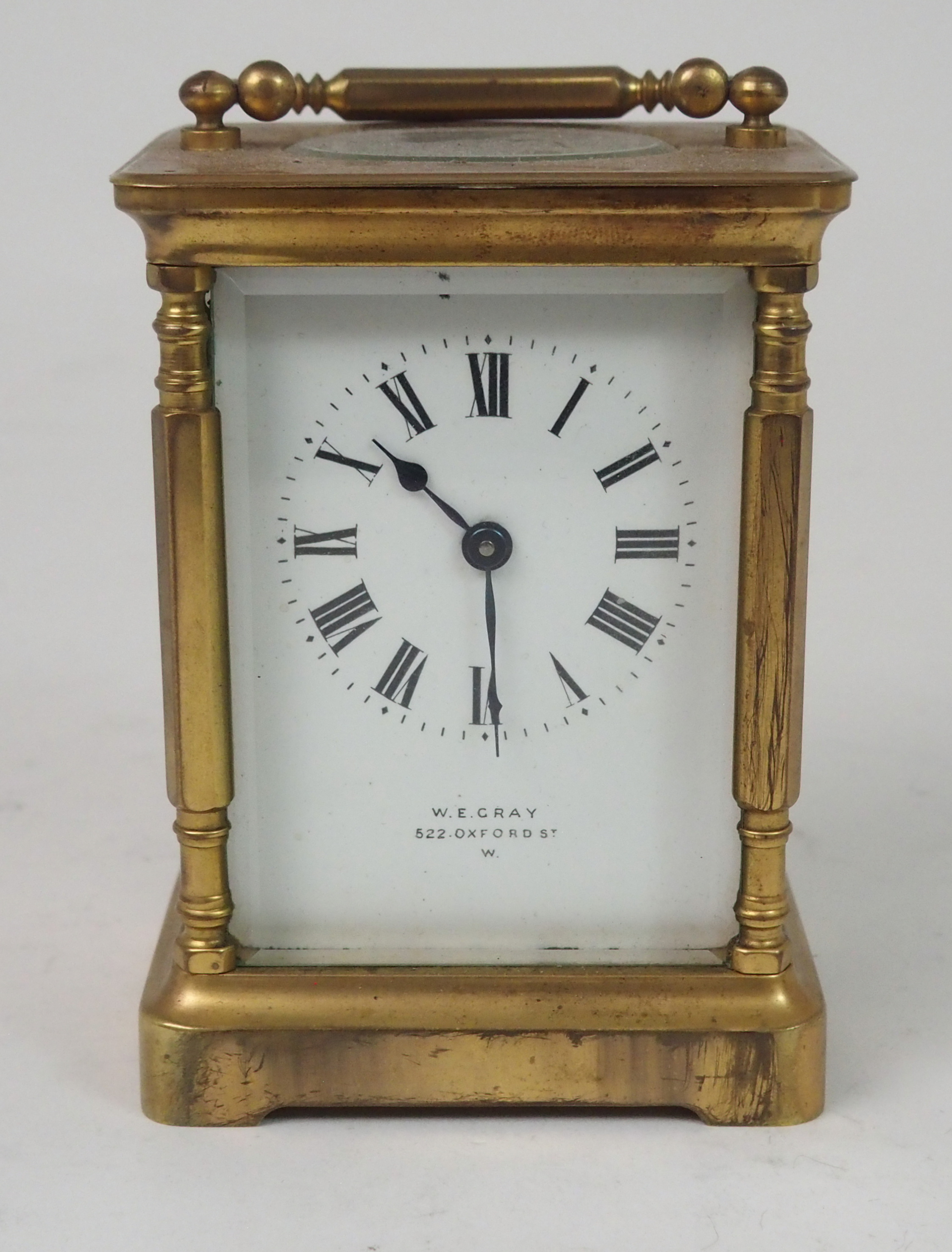 A FRENCH BRASS AND GLASS CARRIAGE CLOCK the white enamel dial with Roman Numerals, retailed by W.