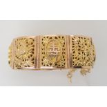 A 14K GOLD CHINESE BANGLE with alternate repousse panels of floral themes and Chinese symbols,