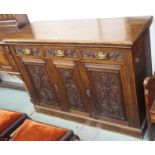 An oak sideboard with three carved drawers over two doors, 100cm high x 137cm wide x 50cm high