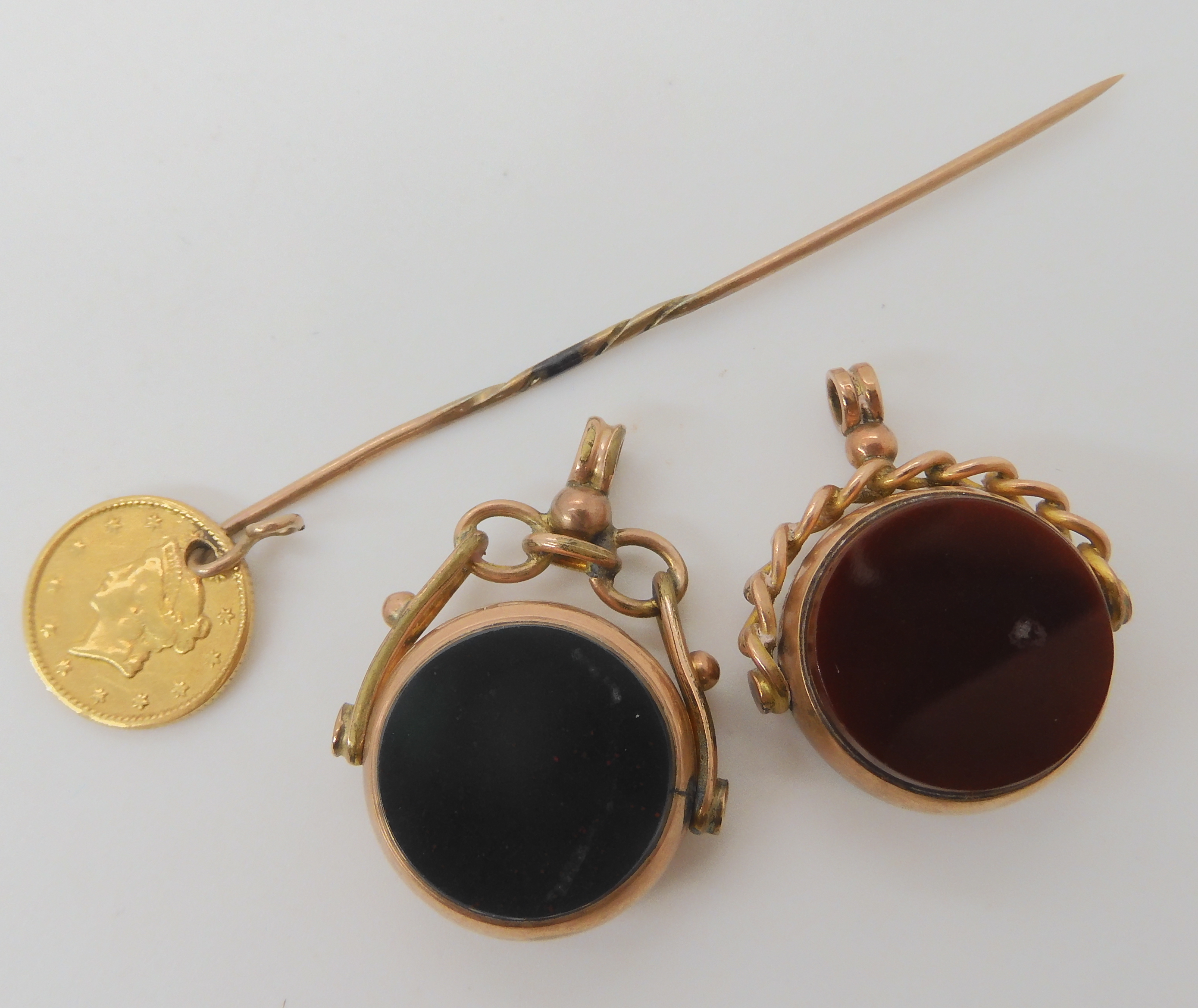 Two 9ct gold double sided agate fob seals, and a stick pin with an attached 1853 1 dollar USA
