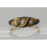A bright yellow metal locket back mourning ring with black enamel and set with pearls, size approx