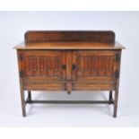 A small early 20th century oak sideboard, the bevelled top over a pair of shallow carved hinged