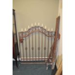A painted cast iron garden gate, of arched form, with scrolling frame and pointed finials, 138 x