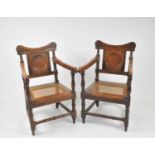 A pair of 19th century oak armchairs, with shallow carved rails above panelled backs, with swept