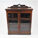 An Edwardian mahogany bookcase, the hinged top revealing a vacant compartment beklow a pierced and