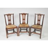 A trio of 18th century country oak dining chairs, with pierced splat backs and drop-in rush seats,