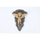 A late 19th century gilt and painted carved wooden boss, decorated centrally with a winged cherub,