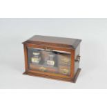 A small oak desk / stationary cabinet, with a hinged top over a bevelled glass front, enclosing a