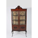 A small mahogany display cabinet, with astragal glazed hinged doors enclosing a shelved interior,