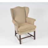 An upholstered wing armchair in the George III style, raised on square mahogany legs, 102cm high, 75