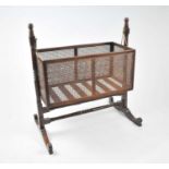 A Victorian mahogany framed bergere crib, rocking on brass mounts, 115cm high, 46cm deep, 105cm