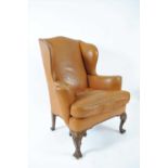 A tan faux leather upholstered wing back armchair