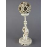 A large Canton carved ivory puzzle ball on figural stand, Qing dynasty, late 19th century, the