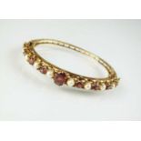 A 9ct gold garnet and pearl bangle