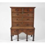 An early 18th century oak chest on stand, inlaid with stringing, the cornice above two short and