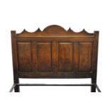 An 18th century and later oak double bedhead and footboard, the headboard with an arched cresting