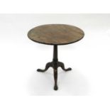 A George III yew tripod table, with a three-piece circular tilt-top and downswept legs terminating