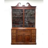 A George III mahogany secretaire bookcase, the upper section with a broken swan-neck pediment and