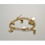 A yellow metal curb link bracelet with attached charms