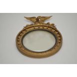 A Regency style convex wall mirror, with a beaded border and carved eagle surmount, 65cm diameter