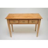A pale pine side table, the planked top with a bevelled border, over three drawers, fitted with