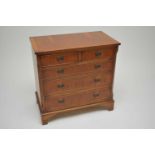 A yew veneered chest of two short and three long drawers, raised on bracket supports, 73cm high,