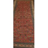 An Eastern woven wool rug, the red field decorated with central foliate motifs, within concentric