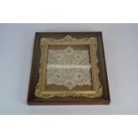 A 19th century moulded gilt gesso frame, with a small lace panel, set in a glazed rosewood box frame