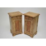 A pair of pale pine bedside cupboards, each with single short drawers and hinged panelled doors,