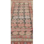 A small old eastern woven wool runner, decorated with a field of stylised medallions 244 x 97 cm.