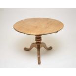 A rustic pale pine tilt-top table, raised on a turned column and three swept legs, 71cm high,