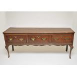 A George III country oak sideboard, the planked top over three equal drawers, fitted with brass