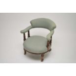An Edwardian upholstered tub chair. with turned mahogany supports and legs on castors, 68cm high,