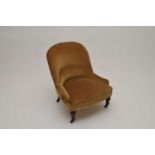 A small, low Victorian upholstered armchair, covered in a gold draylon.