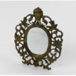 An Edwardian brass easel back mirror, of oval form and cast with scrolling foliage around a shell