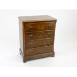 A small reproduction walnut chest of four long drawers, raised on bracket feet, 61cm wide, 65cm