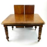 An Edwardian walnut wind-out dining table, the moulded top with rounded corners, raised on turned