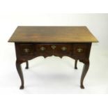 A reproduction oak lowboy, early 20th Century, with three frieze drawers above a shaped apron,