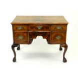An early 18th century walnut veneered lowboy, with a quarter veneered, feather banded and
