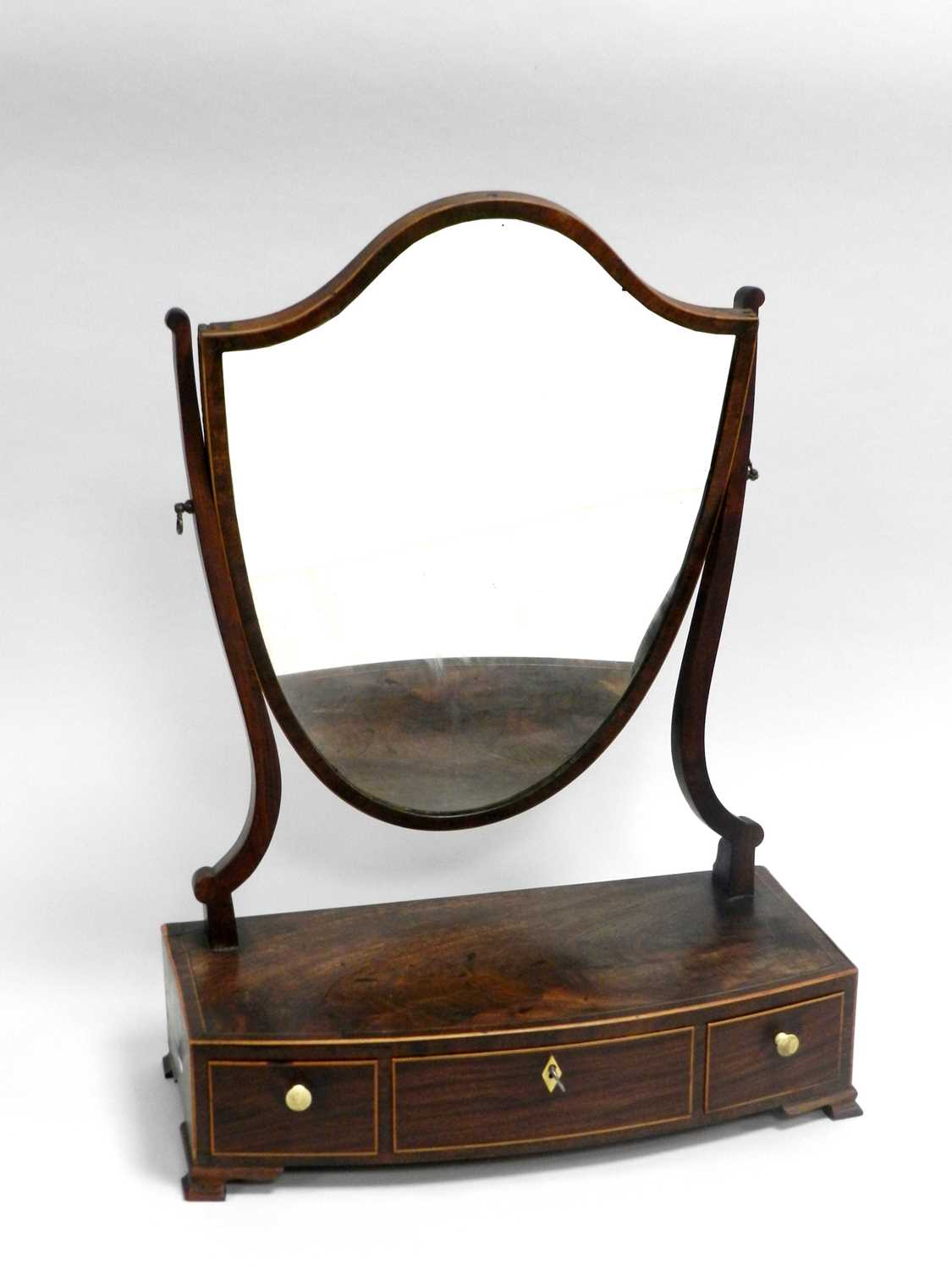 A George III boxwood strung mahogany bow front toilet mirror, the shield plate above three