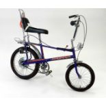 A Raleigh Chopper MkII bicycle, in Ultraviolet livery with orange decals.
