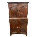 A 19th-century oak court cupboard, the cavetto cornice above twin paneled doors opening to a