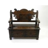 An Edwardian carved oak monks bench, 107cm wide, together with a small carved oak stool of similar