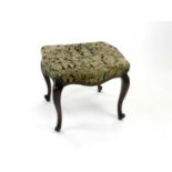 A late Victorian upholstered mahogany stool, with stuff-over seat raised on cabriole supports.