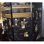 A CHINESE THREE FOLD LACQUER SCREEN inset with ivory and hardstone depicting figures in various purs