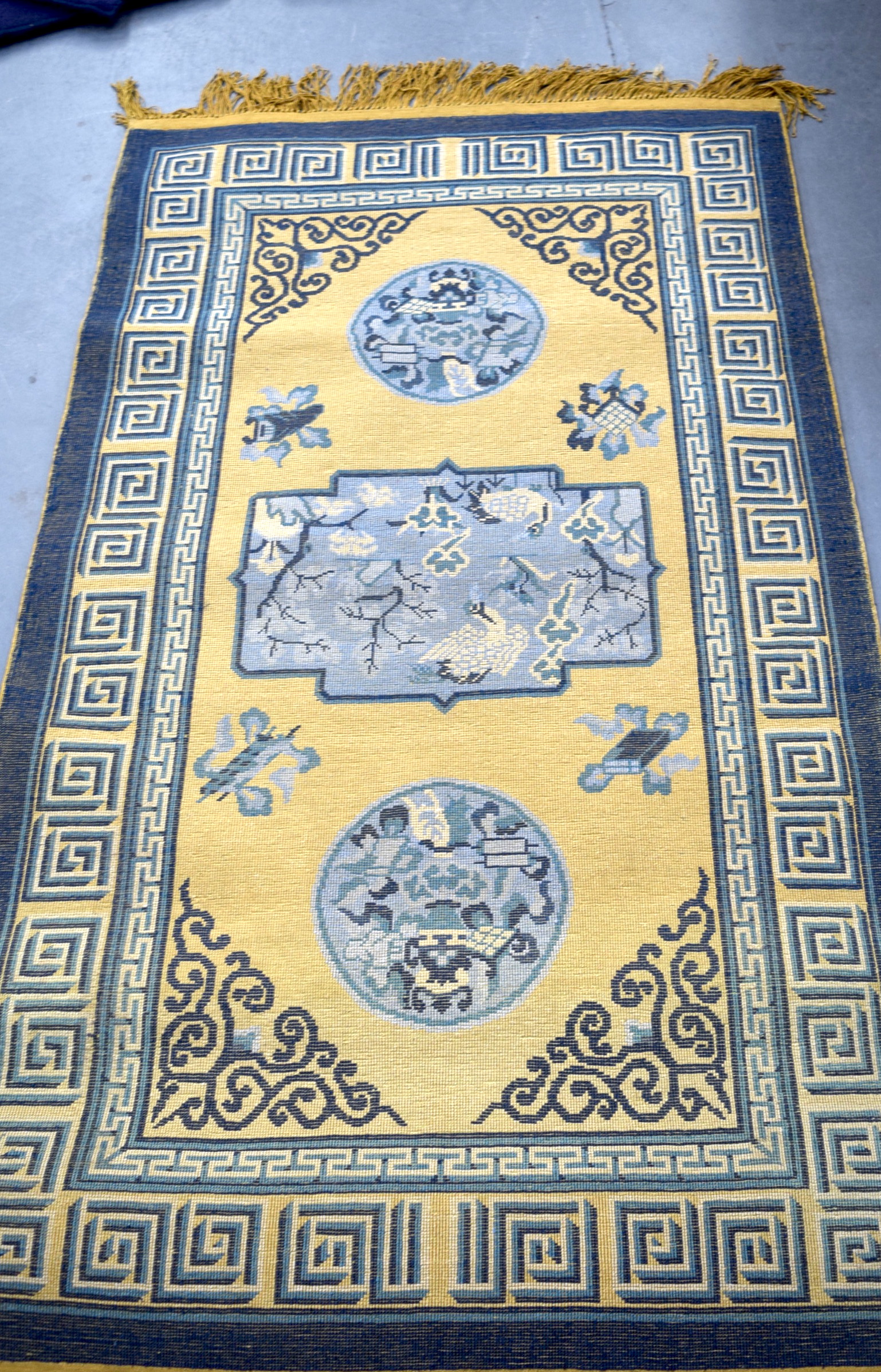 A CHINESE SILK RUG, decorated with panels of birds encased within greek key border. 160 x 91 cm.