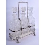 A STYLISH EDWARDIAN THREE PIECE SILVER PLATED DECANTER SET formed with three cut glass bottles. 31