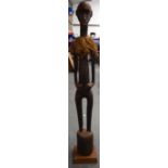 A LARGE MALIAN BAMBARA TRIBAL WOODEN FIGURE, formed standing upon a drum shaped base. 118 cm high.
