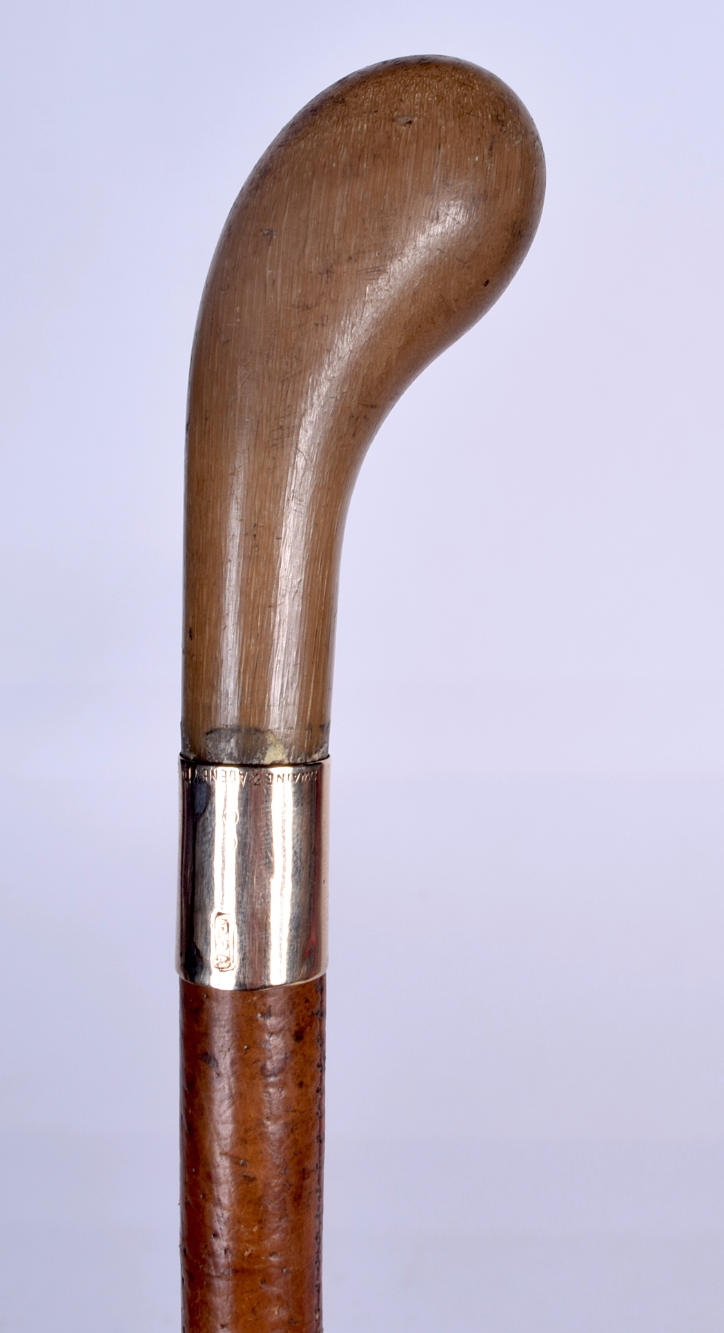 AN EARLY 20TH CENTURY RHINOCEROS HORN HANDLED RIDING CROP, formed with a gold collar. 59 cm long.